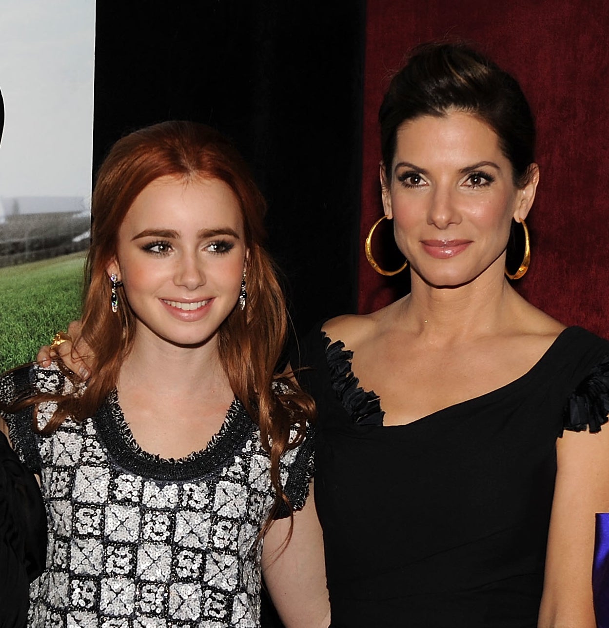 Lily Collins, Sandra Bullock, pose together at an event. Sandra wears a black dress, Lily wears a patterned dress, and Collins wears a dress