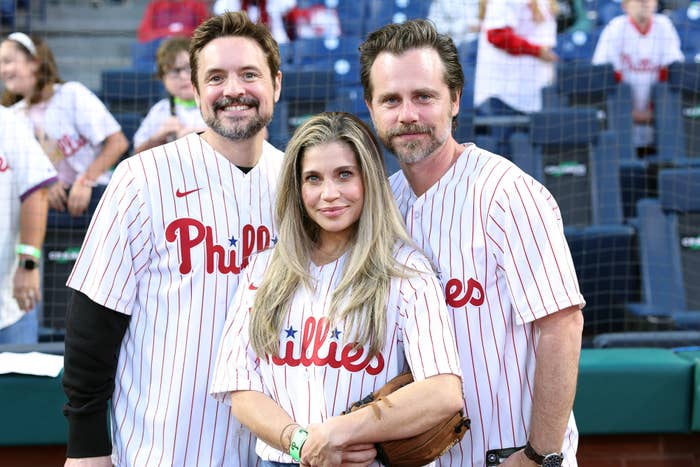 Will Friedle, Danielle Fishel, and Rider Strong are at a Phillies game, wearing Phillies jerseys and smiling at the camera