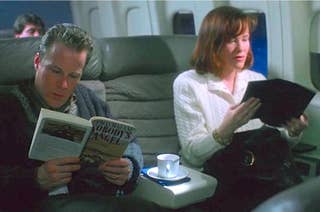 Man and woman reading books on an airplane, seated next to each other in business class