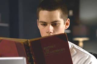 A man with short hair and a white shirt reads a book titled 