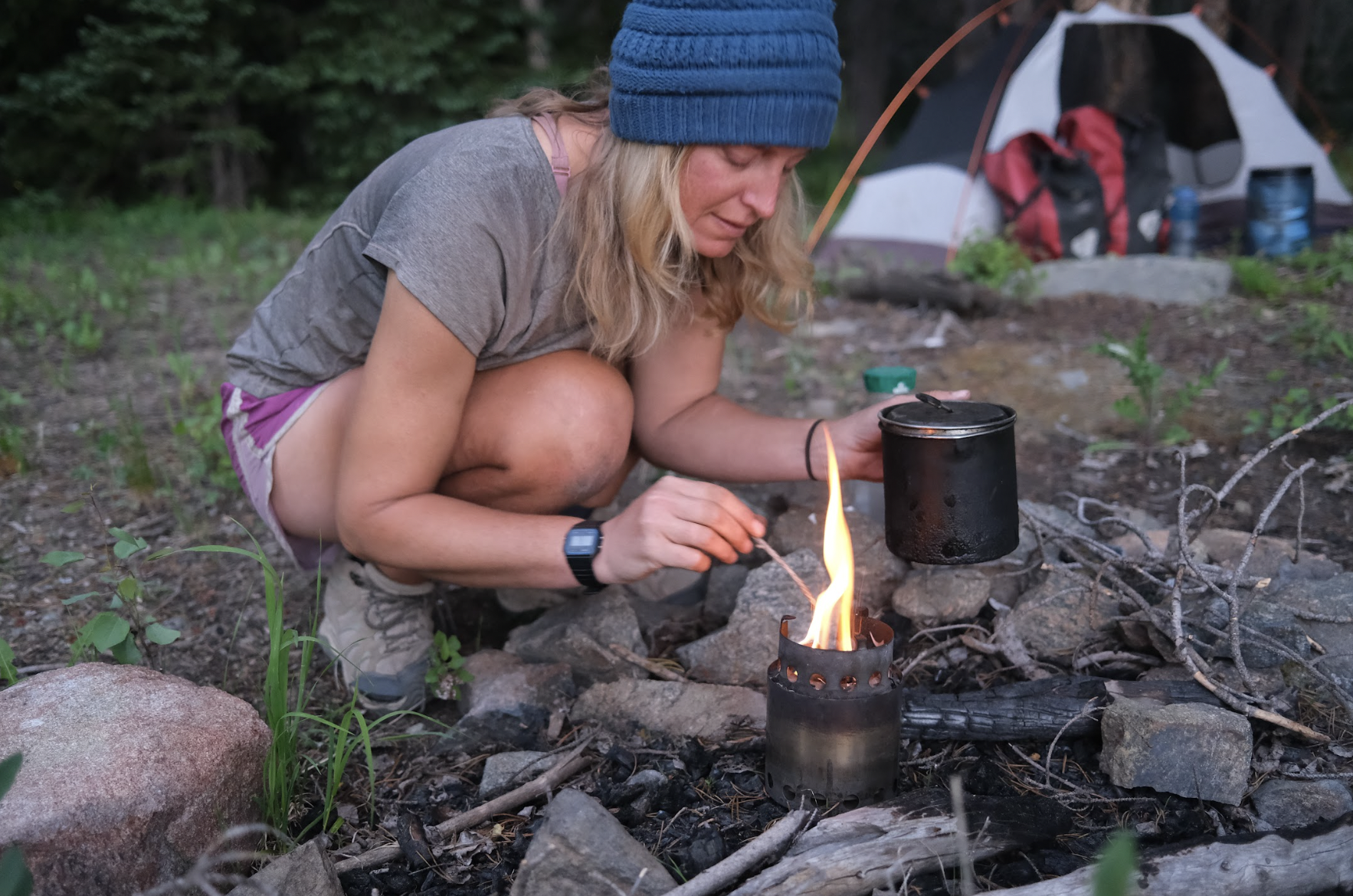 a woman lights a small camp stove